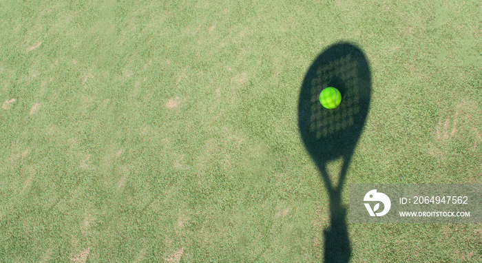 Shadow of a padel racket with a yellow ball on the green grass.