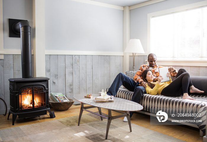 Couple using digital tablet on sofa