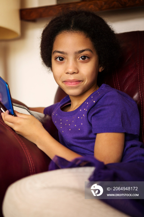 Girl (6-7) on sofa with video game