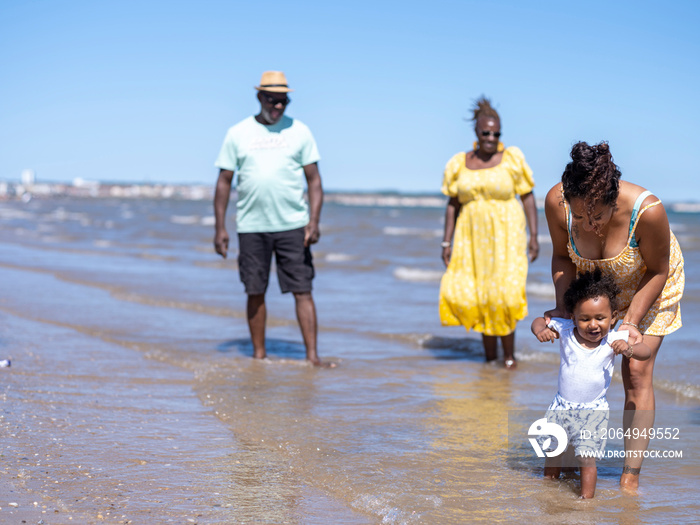 Family with baby boy (12-17 months) wading in sea