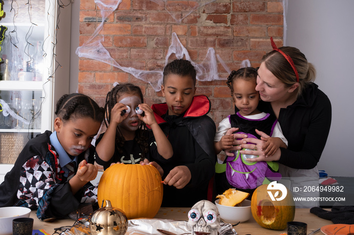 Family in Halloween costumes making Jack�OLantern