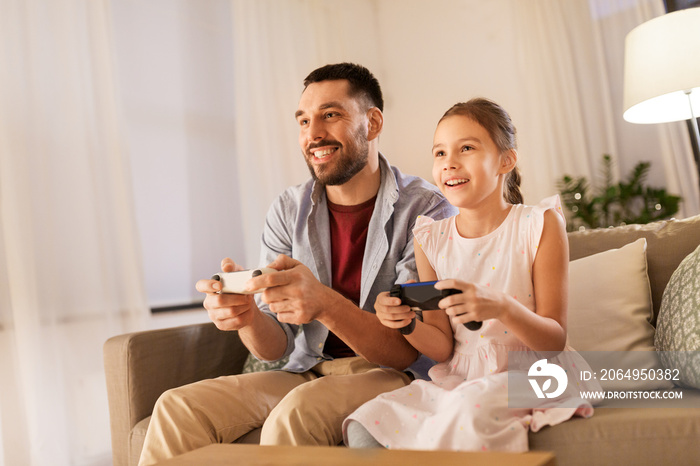 家庭、游戏和娱乐概念-快乐的父亲和带着游戏手柄玩vi的小女儿