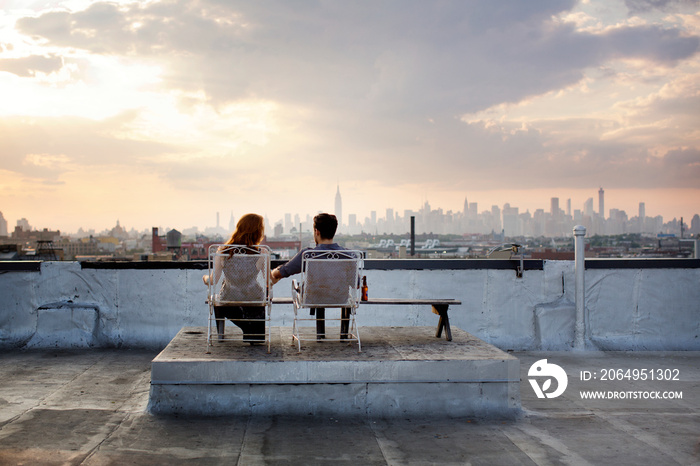 Couple sitting and looking at view from roof of building