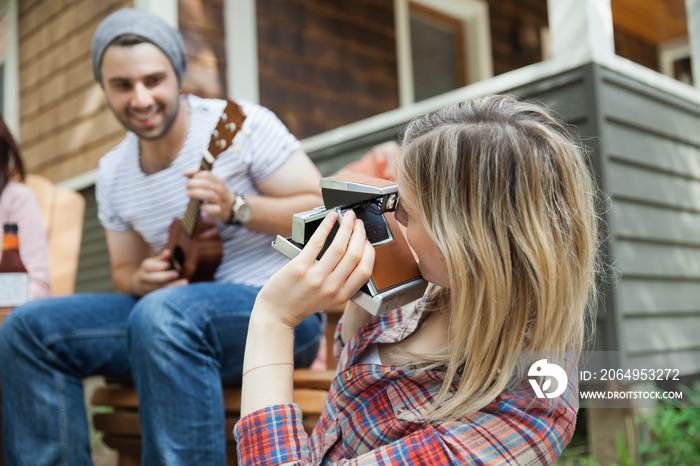 Woman photographing man playing guitar with vintage camera