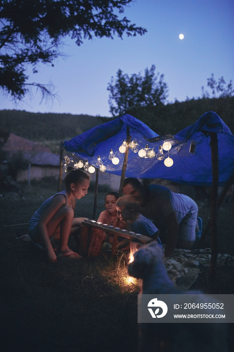 Father with children playing under their backyard tent.