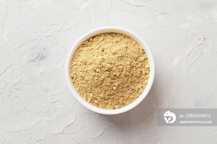 White bowl full of dry ginger on textured background