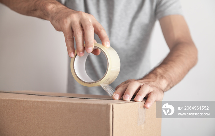 Worker using tape sealing cardboard box. Products, Commerce, Retail, Delivery