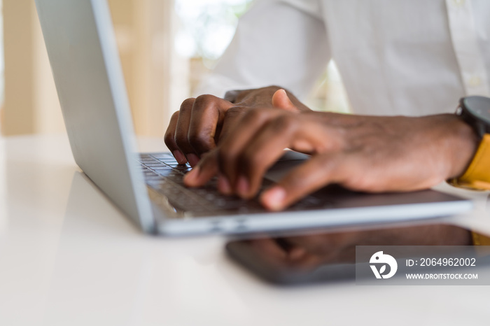 Close up of african business man hands working using keyboard of computer laptop