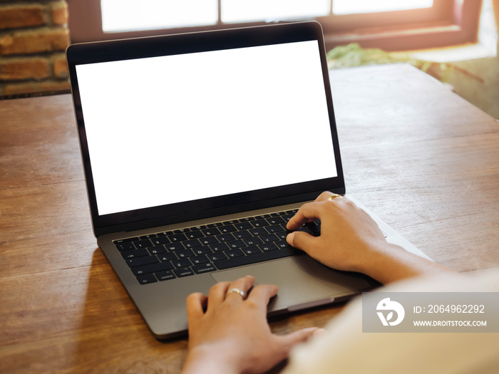 Closeup of womens hand is business working by touching laptop keyboard on wood table in coffee cafe