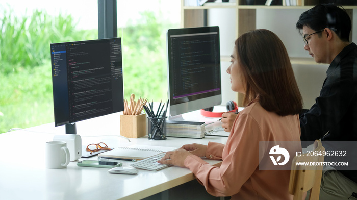 女性程序员在现代办公室使用计算机的侧视图。开发程序。