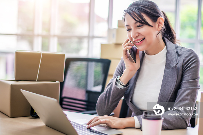 Happy young Asian woman answer phone from customer with her business online shopping at office.