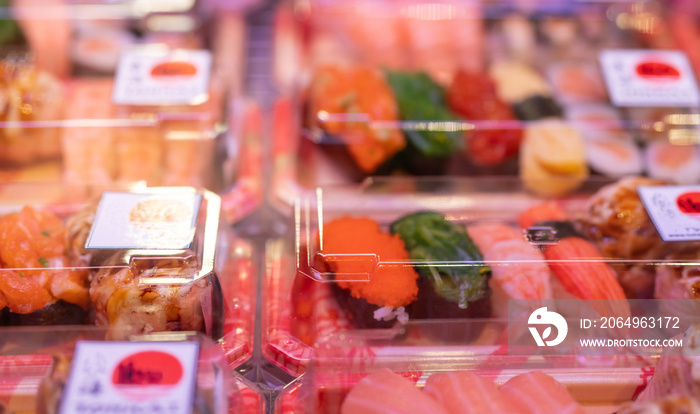 Selective focus on sushi set in plastic box display in shelf at supermarket. Japanese food for take 