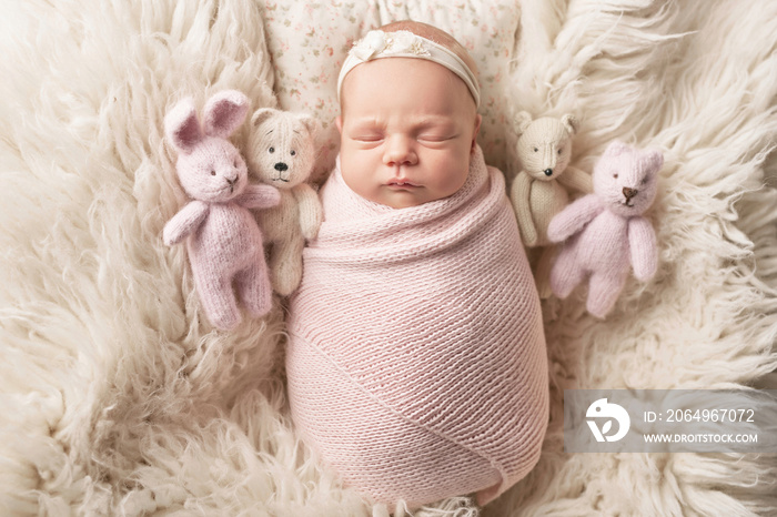 Cute newborn baby girl lies swaddled in a white blanket with toys. Baby goods packaging template. Cl