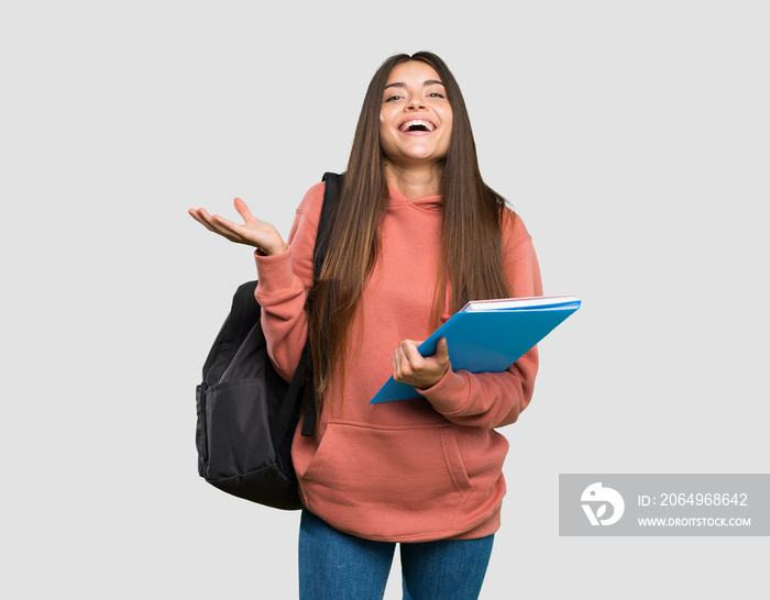 年轻的女学生拿着笔记本，在孤立的灰色背景下微笑着