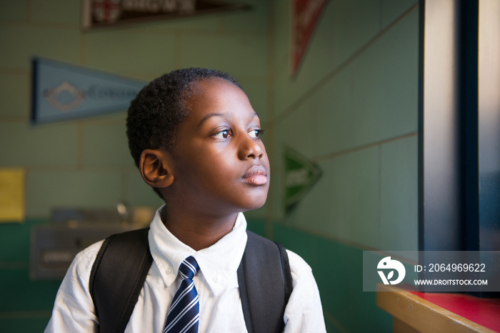 Thoughtful student looking through window in school