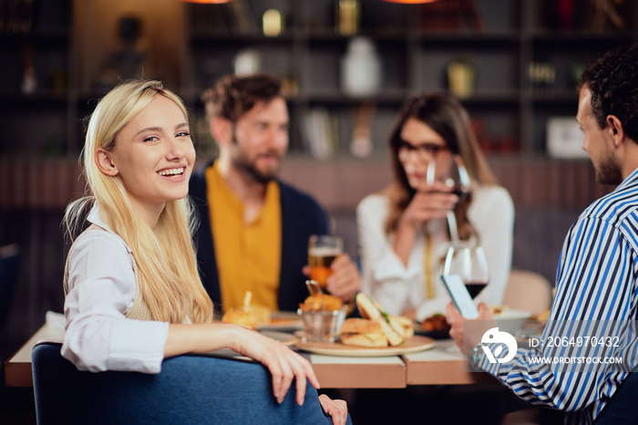 Young smiling Caucasian blonde cute woman dressed smart casual sitting at table in restaurant and lo