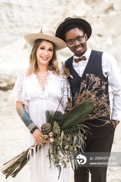 Close up portrait of a boho rustic young interracial couple (African man, Caucasian woman) hugging o