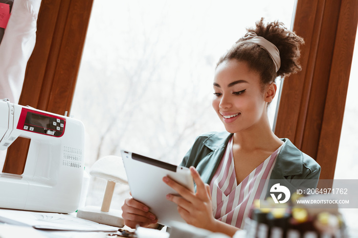 Close-up of young woman tailor with digital tablet is modeling new clothes