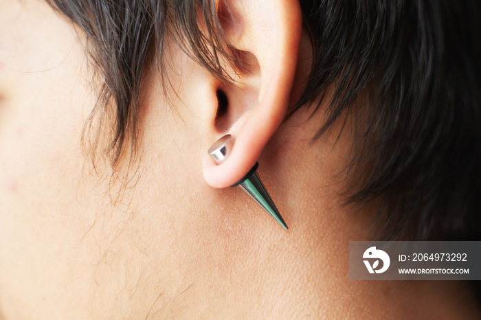 stretching ears for larger diameter tunnels,piercer hand inserts the piercing in the ear