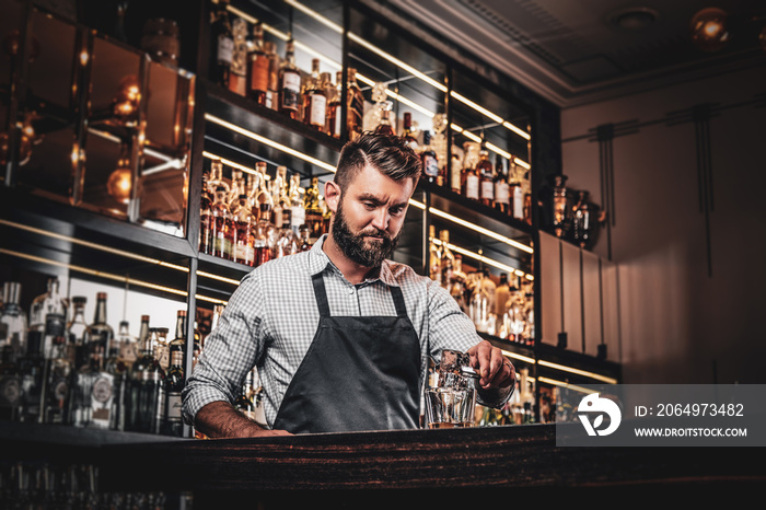 Happy smiling barman is prepairing drinks for customers at posh bar.