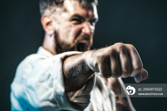 Strong, angry, bearded man dressed in kimono, shaking fist, portrait a screaming boxer. Selective fo