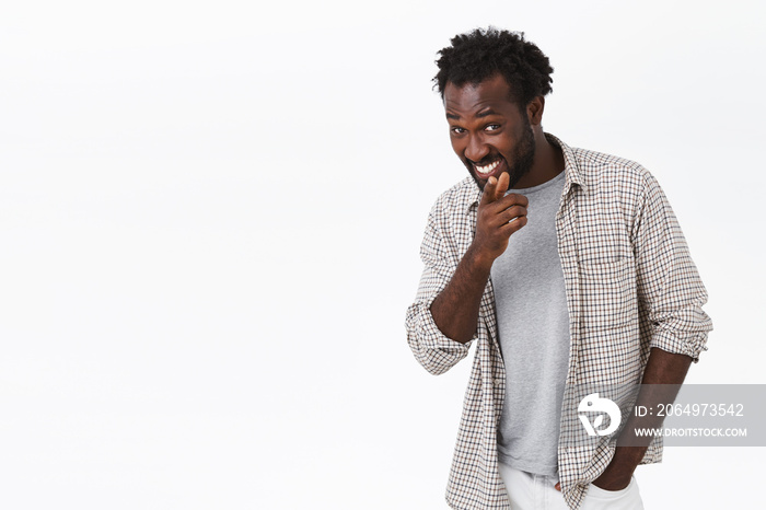 Cheerful, funny and cheeky young african-american bearded man in casual clothes, pointing finger cam