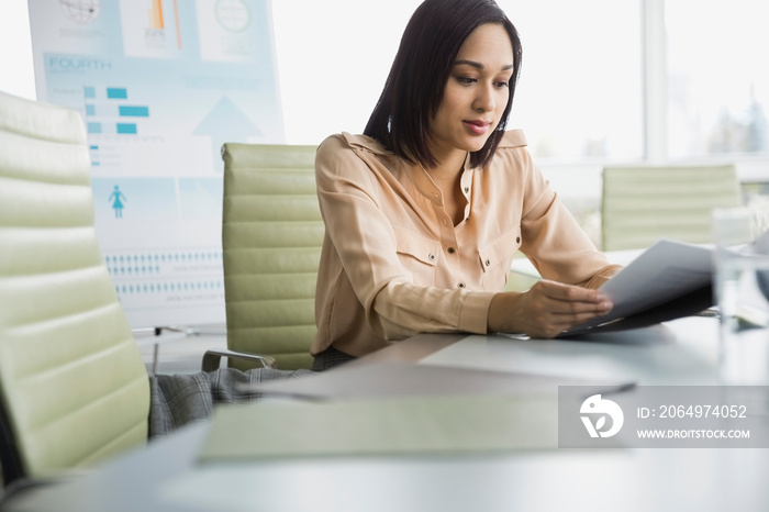 Businesswoman reading document at conference table