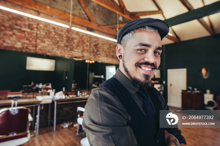 Handsome hairdresser smiling at barbershop