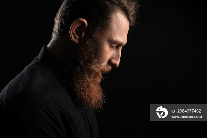 Calm young bearded man on black background