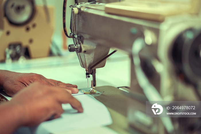 closeup hands worker stitching white fabric on sewing machine