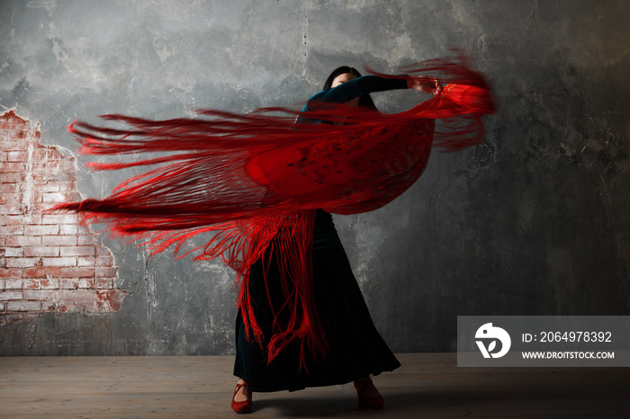 Young adult spanish woman dancing flamenco on gray vintage studio background