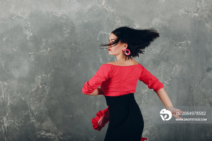 Young adult spanish woman dancing flamenco on gray vintage studio background