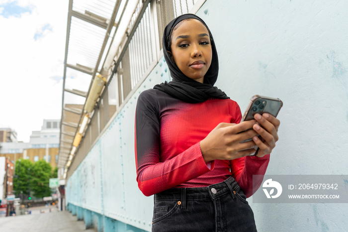 Portrait of young woman wearing�hijab�holding smart phone