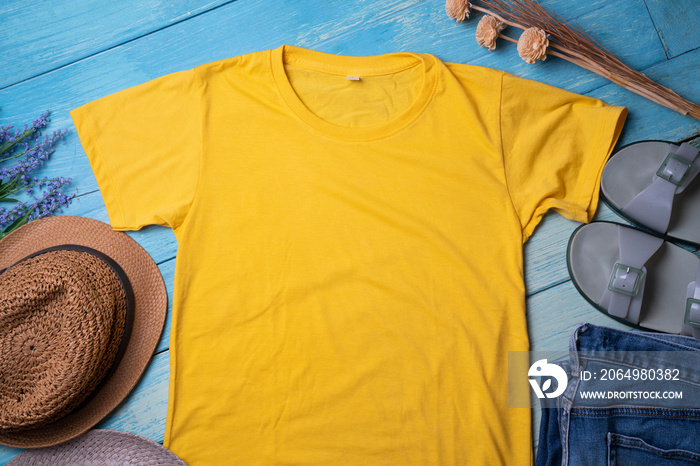 Mockup of a yellow t-shirt blank shirt template with accessories on the blue wooden table background