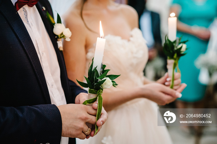 The bride, groom holds in hands wedding candle. Burn candle. Spiritual couple holding candles during