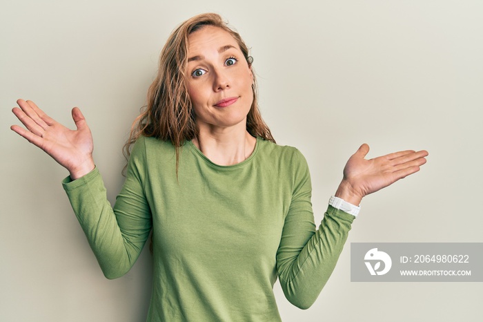 Young blonde woman wearing casual clothes clueless and confused with open arms, no idea and doubtful