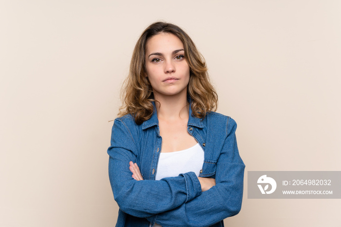 Young blonde woman over isolated background keeping arms crossed