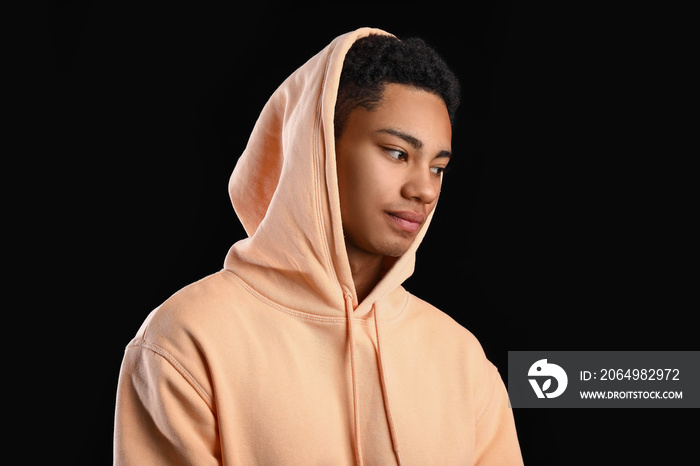 African-American teenage boy in hoodie on black background