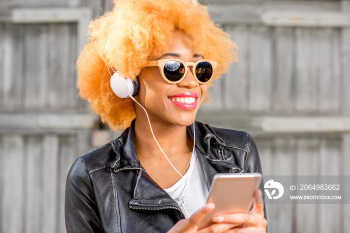 一位穿着皮夹克的非洲女性用智能手机斯坦听音乐的生活方式画像