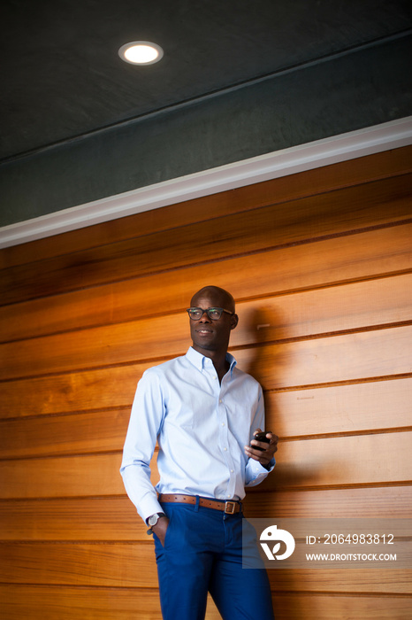 Businessman leaning on wooden wall