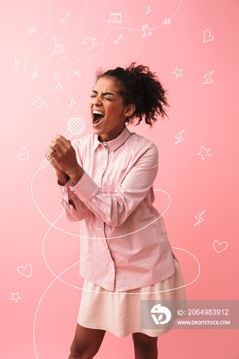 Beautiful young african woman posing isolated over pink wall background screaming singing.