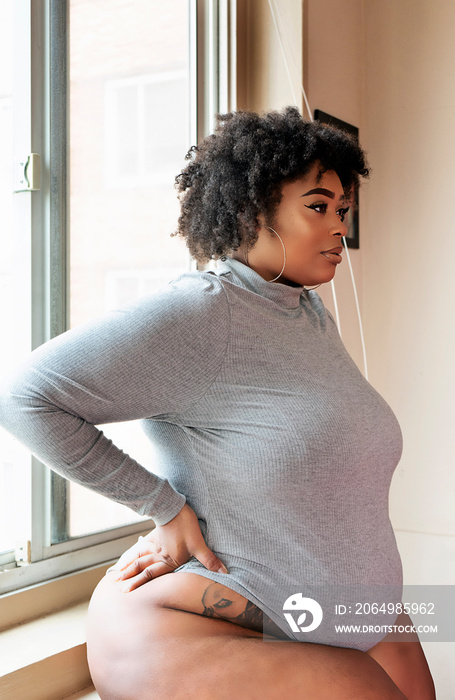 Plus size Black Woman standing in front of a window