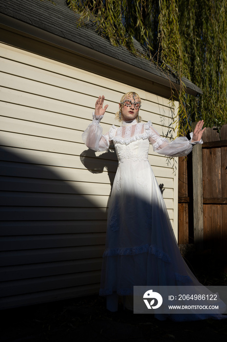 fashion portrait of non-binary person wearing white dress in dramatic sunlight