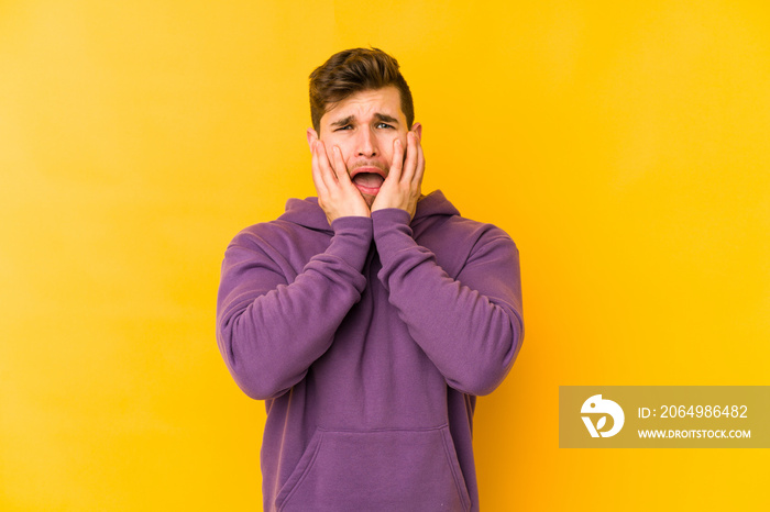 Young caucasian man isolated on yellow background whining and crying disconsolately.