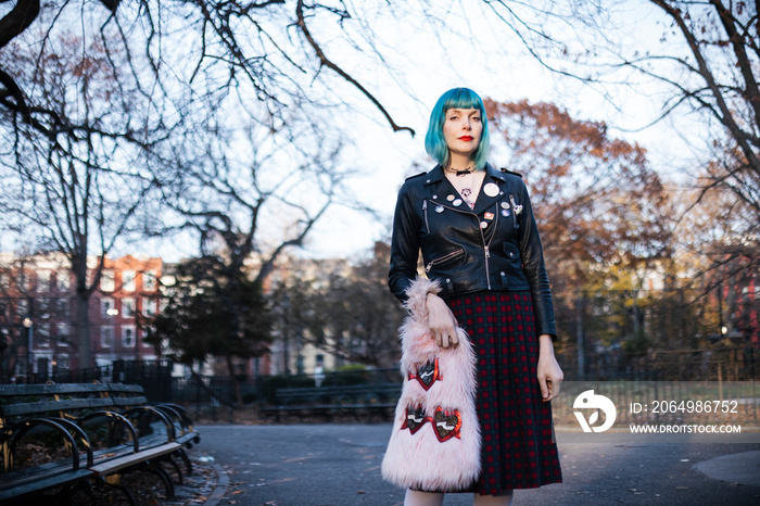 portrait of woman with blue hair and leather jacket in urban park