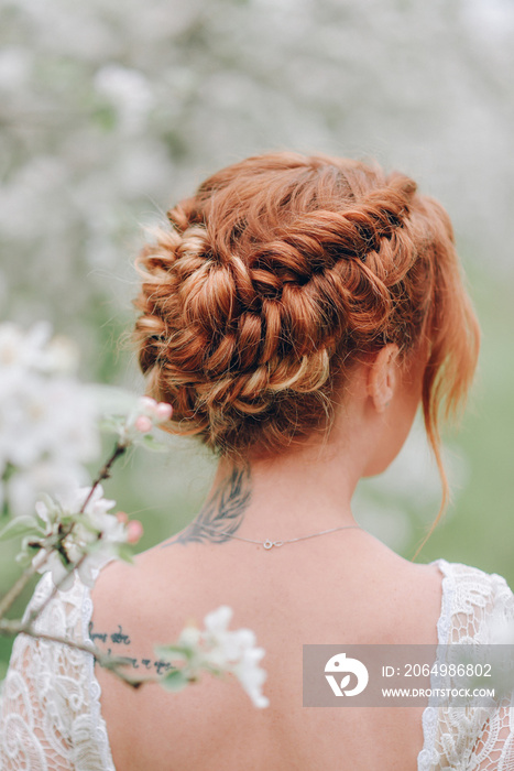 一位红头发的女士背对镜头站在春天开花的花园里。特写发圈