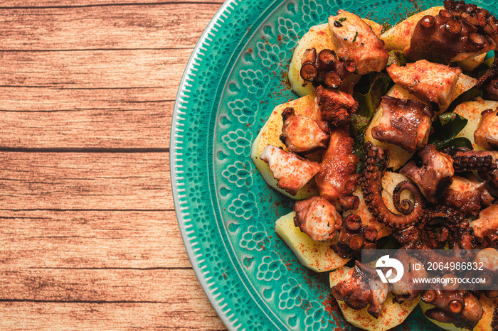 Turquoise plate with Galician octopus on a wooden table. Concept healty food.