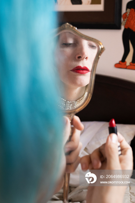 蓝头发女人用古董镜子涂口红
