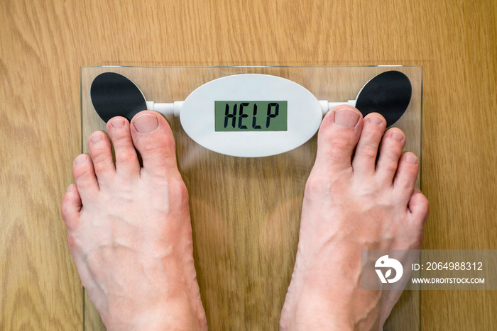 Feet on a bathroom scale with the word HELP on the screen. Lose weight concept with person on a scal