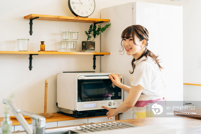 電子レンジを使う女性（笑顔）